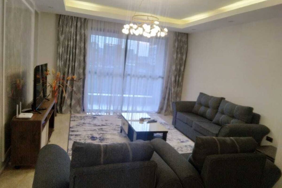 Una sala de estar moderna con un sofá, una mesa de centro y un televisor sobre un mueble.