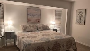 A bedroom with a large bed, two bedside tables with lamps, a painting on the wall, and a seahorse artwork. - Rotonda Heights Pool Home (Rotonda West)