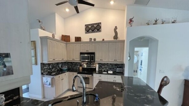 A modern kitchen with white cabinets, a black countertop, and a ceiling fan. - Rotonda Heights Pool Home (Rotonda West)