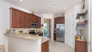 A modern kitchen with wooden cabinets, a granite countertop, stainless steel appliances, and a small island. - This vacation rental home offers a spacious layout  (Rotonda West)