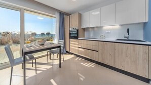 A modern kitchen with a dining area, large windows, and a view of the outdoors. - Sea View Studio Superior (Umag)