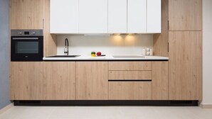 A modern kitchen with wooden cabinets, a built-in oven, and a countertop with a faucet. - Sea View Studio Superior (Umag)