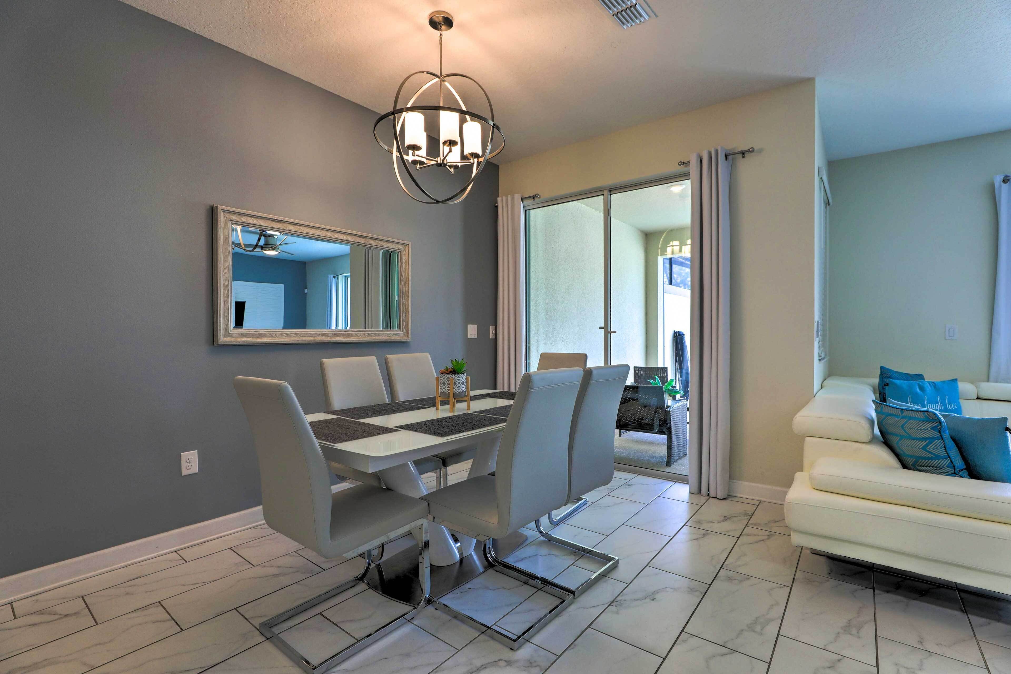 A dining area with a table and chairs, a large mirror, and a chandelier.