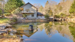 A two-story house with a balcony, a pond in front, and a stone bridge.