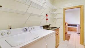 A laundry area with a washing machine, a sink, and metal shelves.