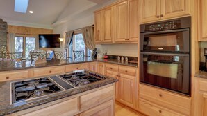 A kitchen with wooden cabinets, a stainless steel stove, and a large oven.