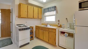 Une cuisine de taille réduite, avec des meubles en bois, une cuisinière blanche, un évier et un four à micro-ondes.