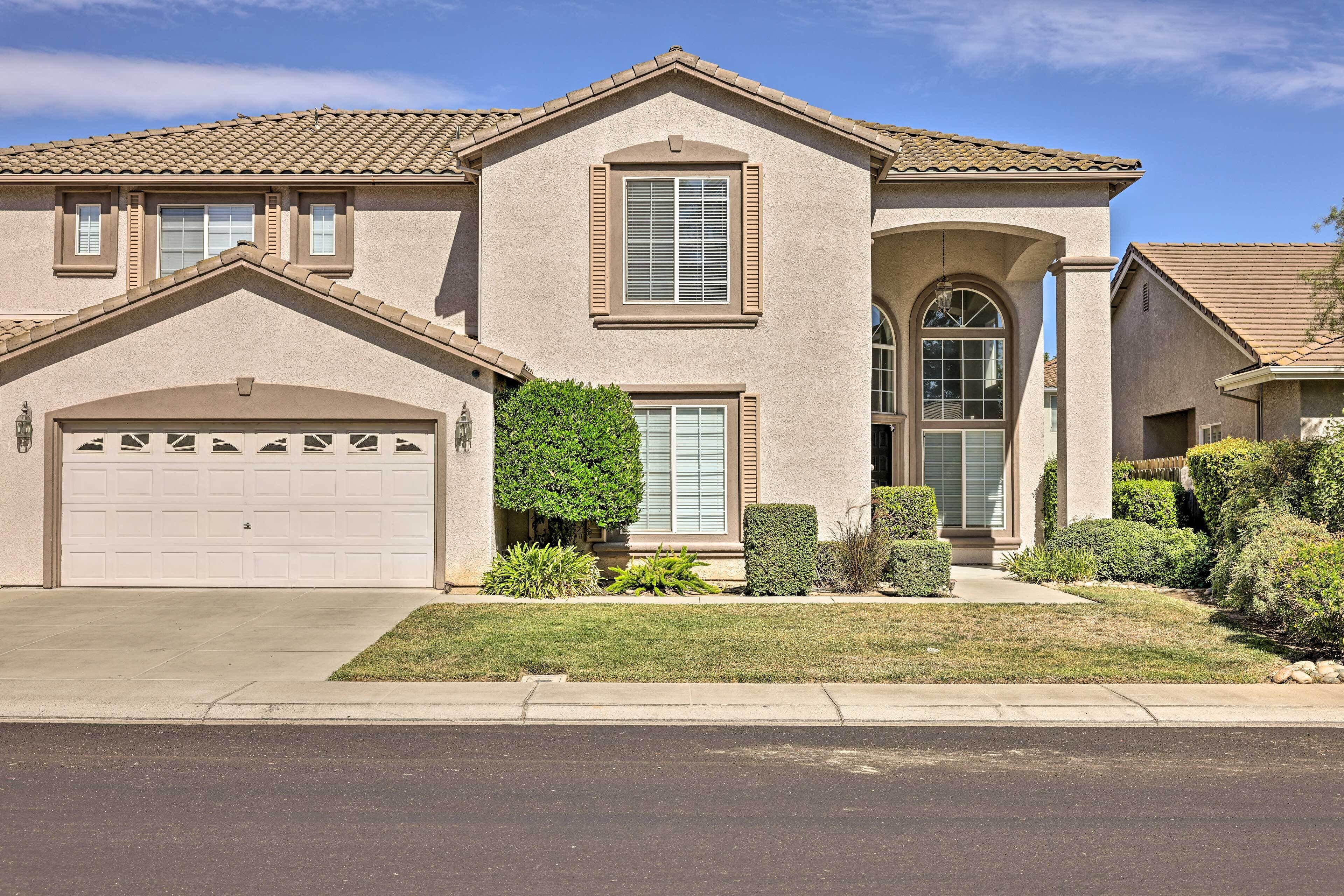 A two-story house with a garage, a front entrance with a door and window, and a small front yard with landscaping.