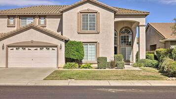 A two-story house with a garage, a front entrance with a door and window, and a small front yard with landscaping.