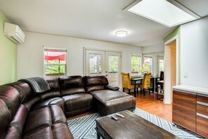 A living room with a sectional sofa, a coffee table, and a dining area with chairs and a table. - Charming Unit w/ Deck ~ 3 Mi to Lake Washington! (Newcastle)