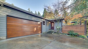 Un garage attenant à une maison, doté d’une grande porte en bois, d’une allée en béton et d’une clôture en bois.