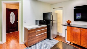 Une cuisine compacte équipée d’un four à micro-ondes, d’un réfrigérateur, de placards en bois et d’un four encastré.