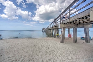 En strand med en træbro, der strækker sig ud i vandet.