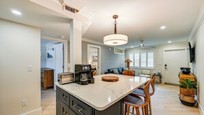 A modern kitchen with a central island, built-in appliances, and a dining area with chairs and a table. - Upscale Naples Condo w/ Pool Access: Walk to Pier! (Naples)