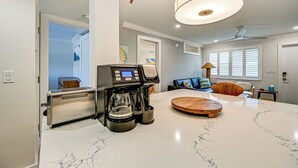 A modern kitchen with a coffee maker, a marble countertop, and a wooden serving tray. - Upscale Naples Condo w/ Pool Access: Walk to Pier! (Naples)