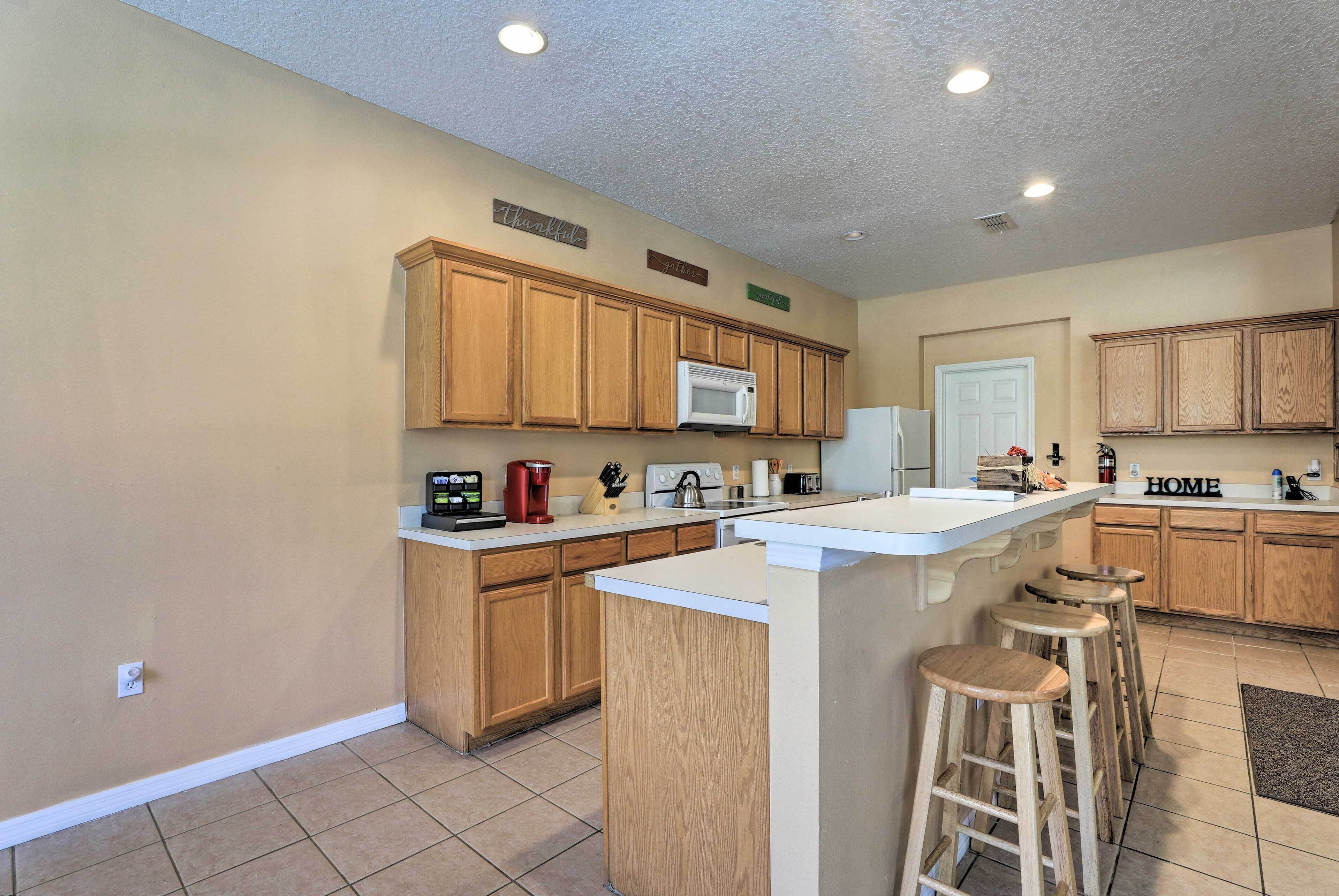 A kitchen with wooden cabinets, a white countertop, a built-in microwave, and a coffee maker.