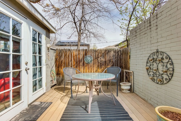 A patio with a round table and chairs, a wooden fence, and a decorative wall.