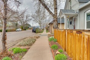 A residential street with houses, a sidewalk, and a wooden fence.