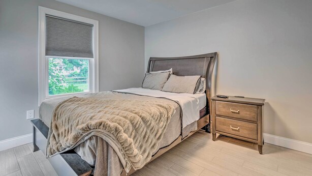 Ein Schlafzimmer mit Bett, Nachttisch und Fenster mit Jalousien.