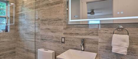 A modern bathroom with a large mirror, a white sink, and a towel rack.