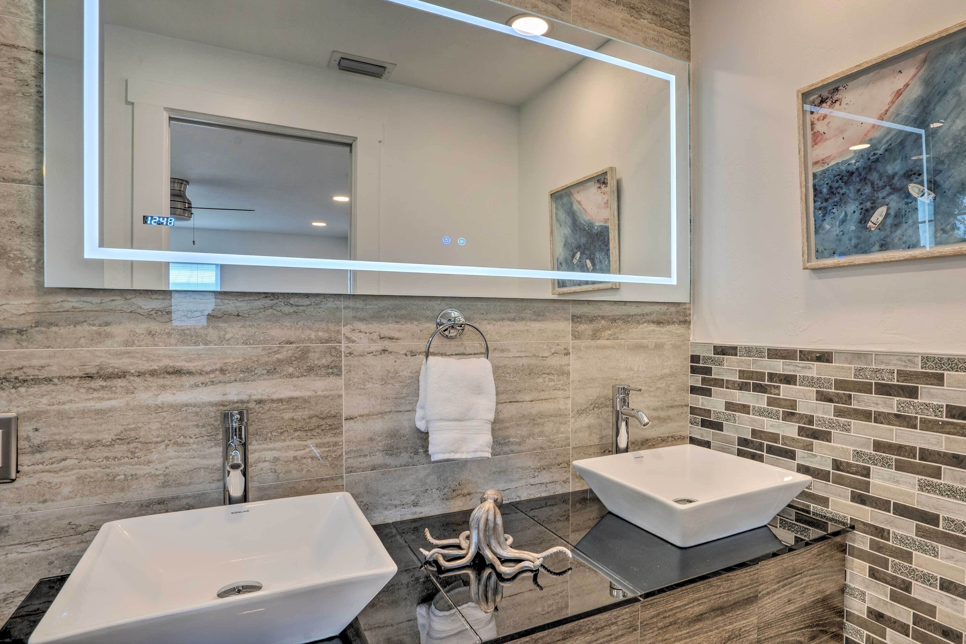 Un baño moderno con dos lavamanos, un espejo grande y un perchero para toallas.