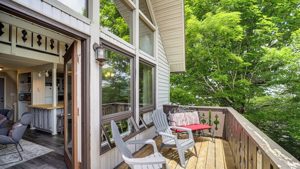 A wooden deck with two Adirondack chairs and a red table, overlooking a lush green forest. - 1 Mi to Beech Mtn Ski Resort: Home w/ Large Yard (Banner Elk)