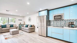 A modern kitchen with blue cabinets, stainless steel appliances, and a patterned backsplash.
