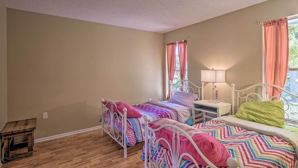 A bedroom with two beds, a nightstand, a small table, and a window with curtains. - Pastoral Naples Home on Working Horse Farm! (Naples)