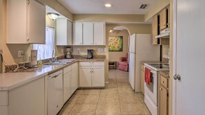 A compact kitchen with white cabinets, a granite countertop, and a stainless steel refrigerator. - Pastoral Naples Home on Working Horse Farm! (Naples)