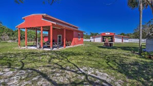 A red building with a covered porch and a small adjacent structure. - Pastoral Naples Home on Working Horse Farm! (Naples)