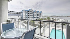 A balcony with a glass table and chairs, overlooking a swimming pool and a marina with boats. - 2 Mi to Ocean City Boardwalk: Gem w/ Pool + Marina (Ocean City)