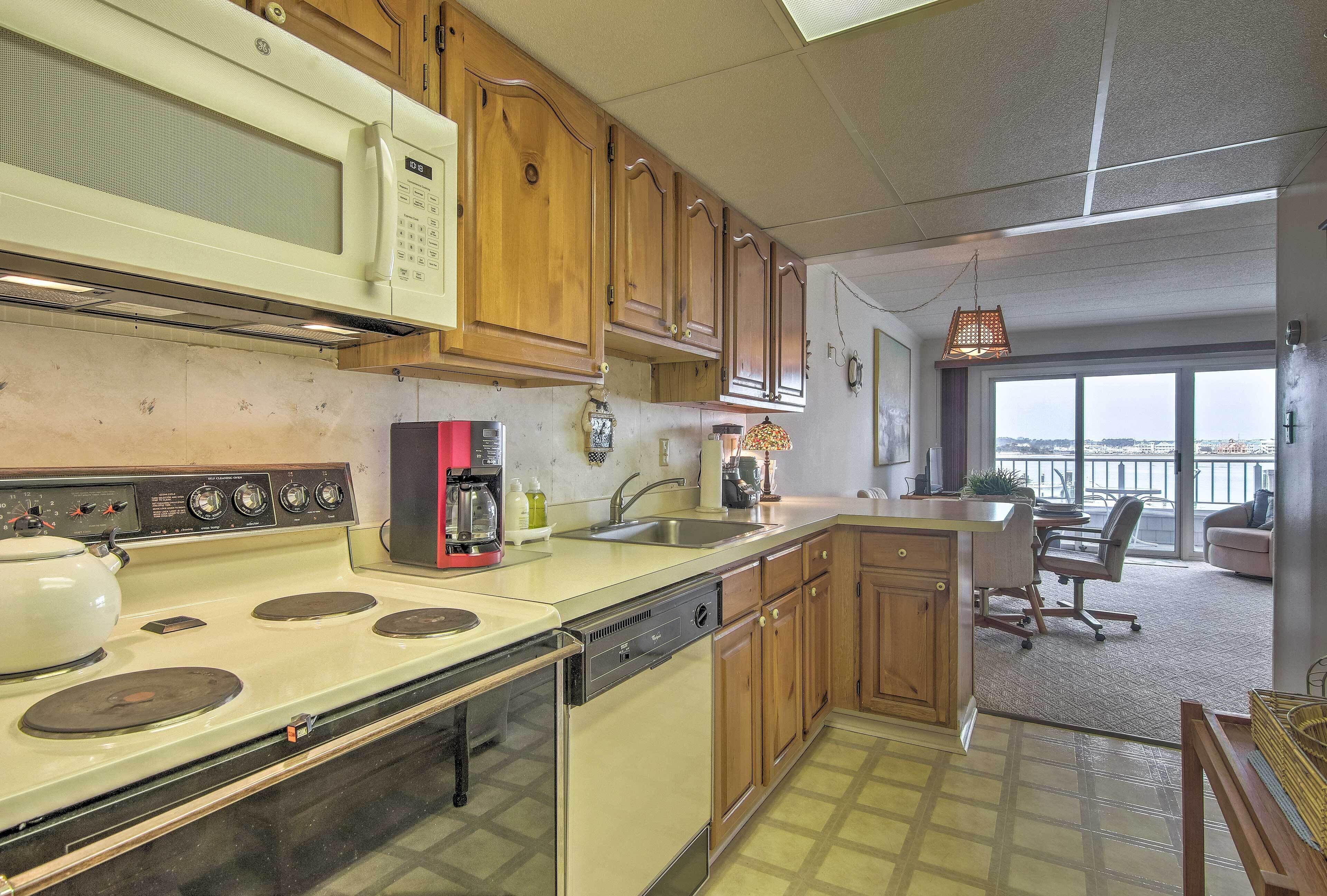 A kitchen with a microwave, stove, and dishwasher. There is a dining area with a table and chairs.
