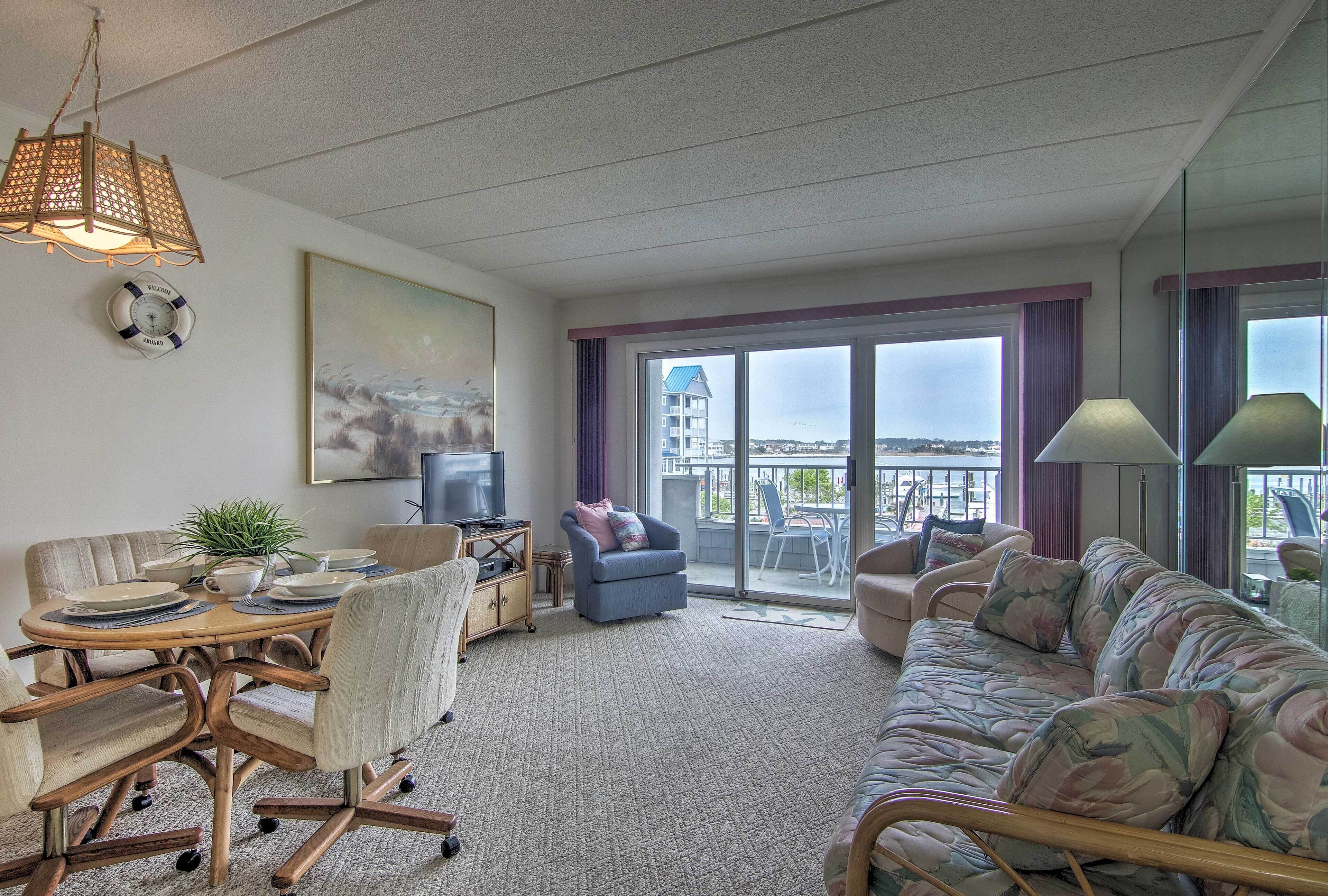 A spacious living room with a dining area, a sofa, a TV, and a balcony with a city view.