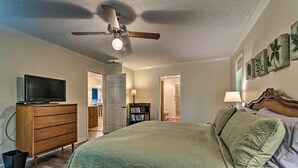 A bedroom with a bed, a ceiling fan, a TV on a dresser, and a bookshelf. - Hot Springs Village Home, Walk to Lake & Golf (Hot Springs Village)