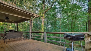 A wooden deck with a covered seating area, a grill, and a view of a forested area. - Hot Springs Village Home, Walk to Lake & Golf (Hot Springs Village)