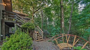 A wooden staircase leading to a covered area, surrounded by lush greenery and a gravel path. - Hot Springs Village Home, Walk to Lake & Golf (Hot Springs Village)