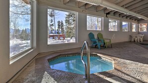 Une pièce avec une piscine, de grandes fenêtres et un espace salon extérieur.