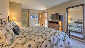 Une chambre avec un grand lit, une commode, un téléviseur et une vue sur un balcon.