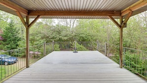 A covered wooden deck with railings, surrounded by greenery and trees. - Dock & Bay Access! Cabin on St. Jeromes Creek (Ridge)