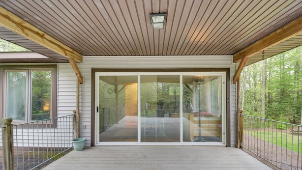 A covered porch with a wooden ceiling, a glass door leading to a deck, and a metal railing. - Dock & Bay Access! Cabin on St. Jeromes Creek (Ridge)