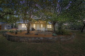 Une maison dotée d’un patio en pierre, d’un espace salon extérieur et de guirlandes lumineuses.