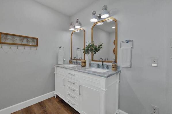 A bathroom with two sinks, a large mirror, and a wooden plant on the counter.