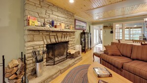 A cozy living room with a stone fireplace, a wooden ceiling, and a brown striped sofa. - Ski & Hike! Creekside Cabin 7 Mi to Linville Falls (Newland)