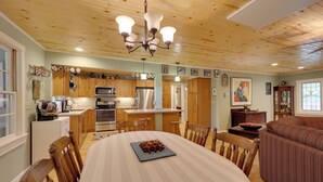 A spacious kitchen with wooden cabinets, a central island, and a dining area with a round table and chairs. - Ski & Hike! Creekside Cabin 7 Mi to Linville Falls (Newland)
