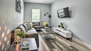 A modern living room with a gray sofa, a coffee table, and a TV mounted on the wall. - Luxe, Modern Houston Apt - 1 Mile to The Galleria! (Houston)