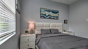 A bedroom with a bed, nightstand, and a window with blinds. - Luxe, Modern Houston Apt - 1 Mile to The Galleria! (Houston)