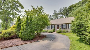 A residential driveway leading to a house with a curved path, surrounded by well-maintained greenery and trees. - Ideal Narragansett Location w/ Furnished Deck! (Narragansett)