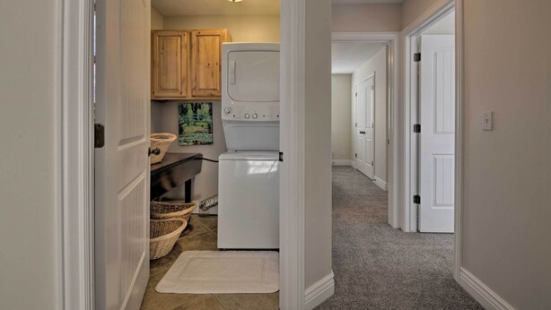 A laundry room with a washer and dryer, wooden cabinets, and a small rug on the floor. - Mountain-view Home < 15 Mi to Alta + Snowbird (Sandy)