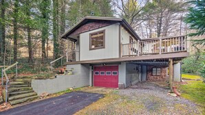 Une maison à deux étages avec une porte de garage rouge, un balcon et un escalier menant à l’étage supérieur.