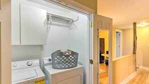 Un espace buanderie comprenant un lave-linge, un sèche-linge et un panier posé sur un meuble.